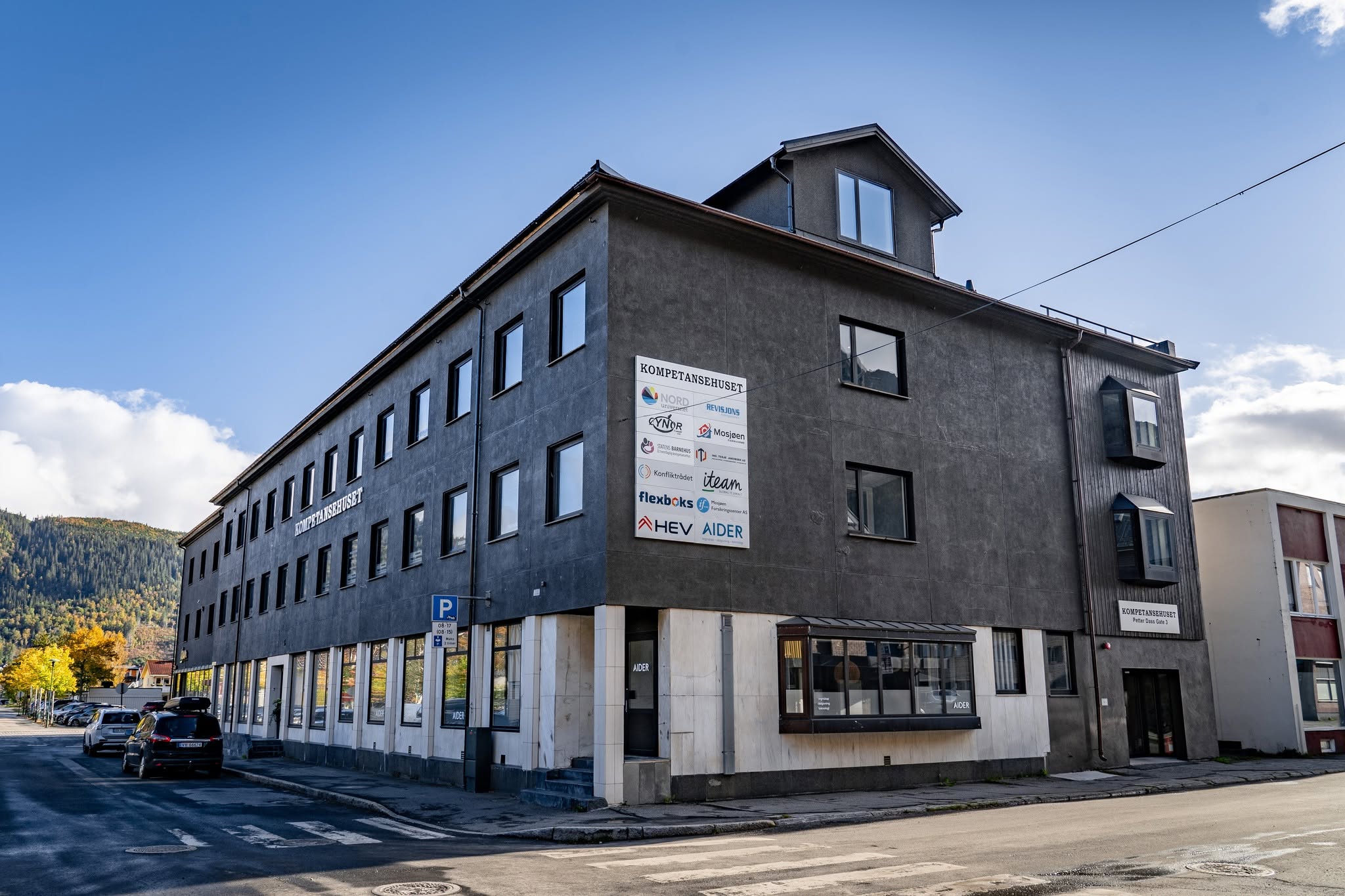 Kompetansehuset på hjørnet av Petter Dass gate i Mosjøen, med mørk fasade og store vinduer.